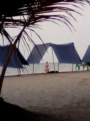 a woman sitting on the beach under a tent at Condominio de Cabañas Cangrejo Azul in El Bobo