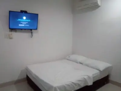 a small room with a bed with a tv on the wall at Condominio de Cabañas Cangrejo Azul in El Bobo