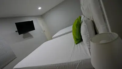 a white bed with a green pillow and a television at Hotel Casa Bellamare in Cartagena de Indias