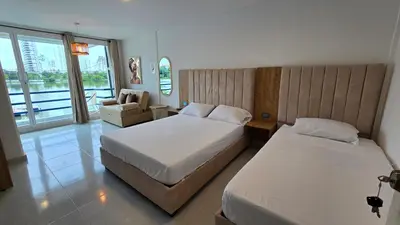 a hotel room with two beds and a chair at MR1-4G APARTAMENTO CERCA LA LAGO CON AIRE ACONDICIONADO Y WIFi in Cartagena de Indias