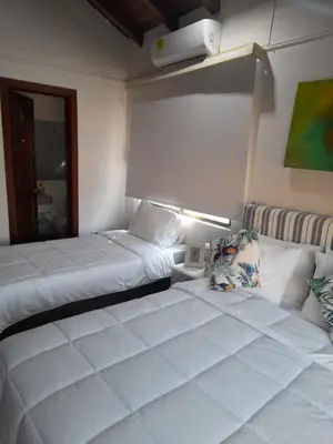 a bedroom with two beds and a lamp on the wall at Condominio Playa Caimán in Coveñitas