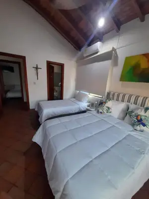 a bedroom with two beds and a cross on the wall at Condominio Playa Caimán in Coveñitas