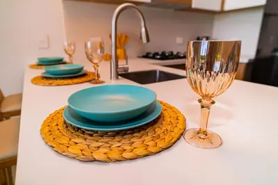 a table with plates and glasses on a kitchen counter at Exclusivo Apartamento en Baia Kristal 1 hab in Cartagena de Indias