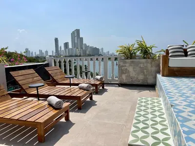 three wooden benches sitting on a balcony overlooking the water at Santa Isabel - Villa de diseño con vistas privilegiadas y piscina in Cartagena de Indias
