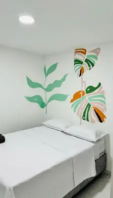 a bedroom with a white bed with a painting on the wall at Hotel Stay Golden in Cartagena de Indias