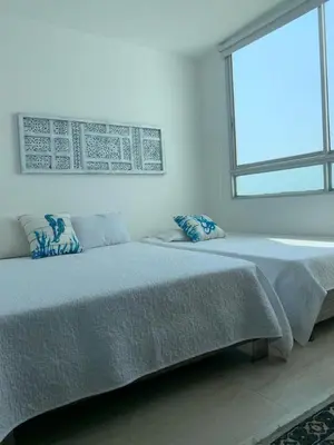 a white bedroom with two beds and a window at Edificio Mares de Coveñas in Coveñas