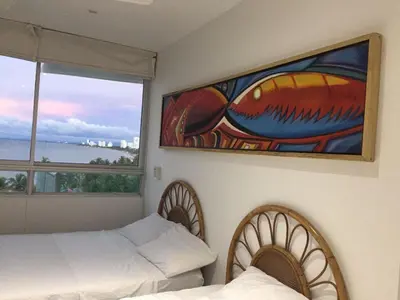 a bedroom with two beds and a painting of a fish at Edificio Mares de Coveñas in Coveñas