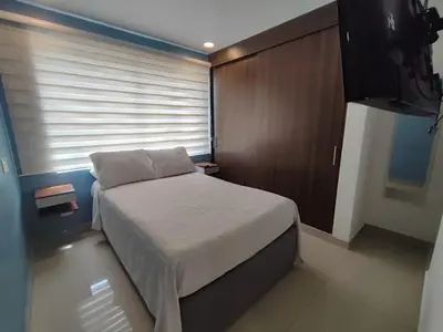 a small bedroom with a bed and a television at Apartamento Cartagena cerca a la playa in Cartagena de Indias