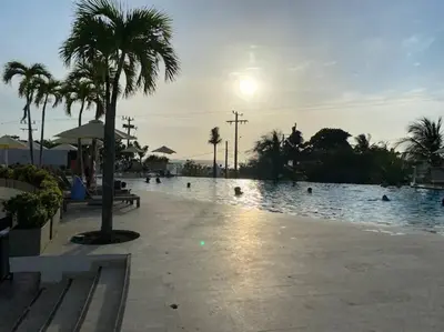 a pool with palm trees in front of a resort at Amazing Beachfront Apartment in Cartagena de Indias