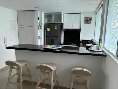 a kitchen with a black counter and two bar stools at Amazing Beachfront Apartment in Cartagena de Indias