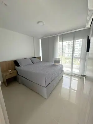 a white bedroom with a bed and a window at Amazing Beachfront Apartment in Cartagena de Indias