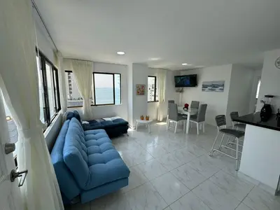 a living room with a blue couch and a kitchen at Portofino Bocagrande 2 habitaciones in Cartagena de Indias