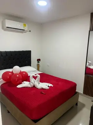 two people with balloons on a bed with a red blanket at Hostel HA1 in Cartagena de Indias