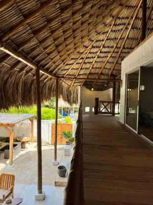 a wooden walkway with a straw roof on a resort at La Mofa Beach House in Bocachica