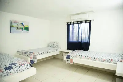 a room with three beds and a window at La Mofa Beach House in Bocachica