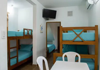 a room with two bunk beds and a table and chairs at Alojamiento Familiar #3 - Un terruño en la costa in Puerto Viejo