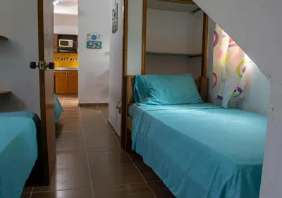 a small room with two beds and a kitchen at Alojamiento Familiar #3 - Un terruño en la costa in Puerto Viejo