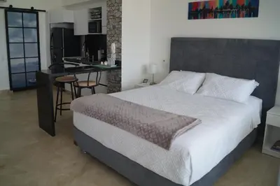 a bedroom with a large bed and a kitchen at Cartagena Aparta Suite Crespo Aeropuerto in Cartagena de Indias