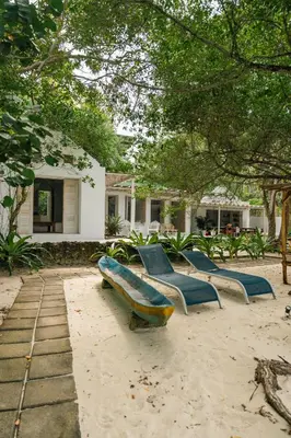 a group of benches sitting in the sand in front of a house at Casa Rosario in Isla Grande