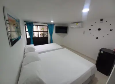 a bedroom with two beds and a clock on the wall at Hostal Doña Betty 2 in Cartagena de Indias