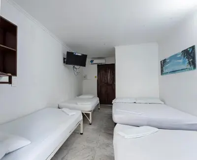 a room with three beds and a tv at Hotel Be Real in Coveñitas