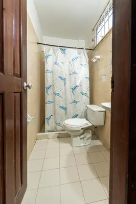 a bathroom with a toilet and a shower curtain at Hotel Be Real in Coveñitas