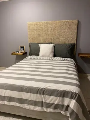 a bed with a striped blanket and a pillow on it at Casa Piedra Barranquilla in Barranquilla
