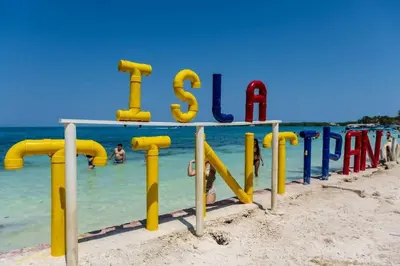 a sign on the beach with people in the water at Caribean campestre in Calao