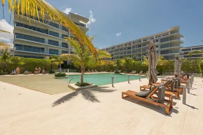 a resort pool with lounge chairs and a palm tree at Frente al Mar, con playa y 4 piscinas en Cartagena in Cartagena de Indias
