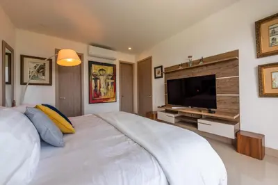 a white bedroom with a large bed and a television at Frente al Mar, con playa y 4 piscinas en Cartagena in Cartagena de Indias
