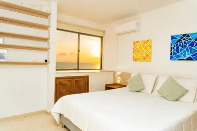 a bedroom with a white bed and a window at Apartamento frente al mar, vista al centro de Cartagena in Cartagena de Indias