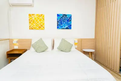 a bedroom with a white bed with two paintings on the wall at Apartamento frente al mar, vista al centro de Cartagena in Cartagena de Indias