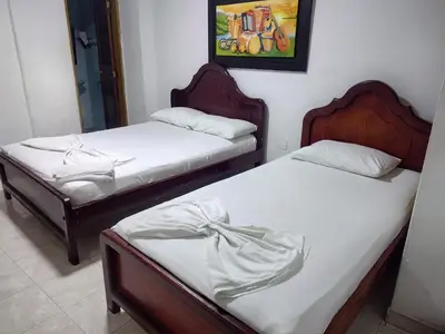 two twin beds in a room with a painting on the wall at Hotel Tamaulipas Mixteca in Sincelejo