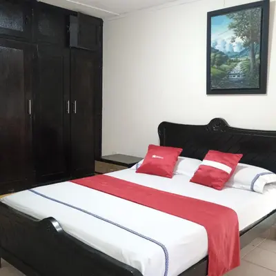 a bedroom with a large bed with red pillows at Hotel Villa Giron inn in Barranquilla