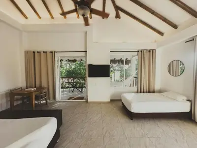 a bedroom with a bed and a desk and a table at SABAI Beach Hotel in Baru
