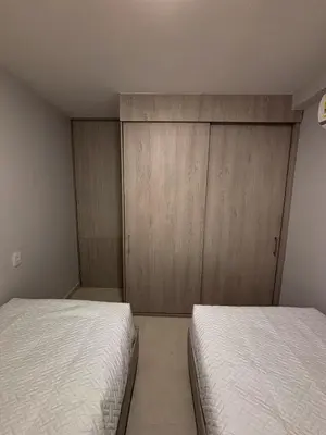 a bedroom with two beds and wooden cabinets at Apartamento La Plazuela Barranquilla in Barranquilla