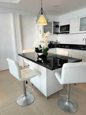 a kitchen with a black counter and white chairs at Alojamiento Cartagena frente Al Mar in Cartagena de Indias