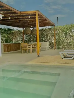 a patio with a table and a pavilion over a pool at Casa frente a la playa in Salina de Rey