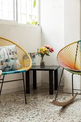 a room with two chairs and a table with a vase of flowers at MANGO BiCHE - HOUSE in Cartagena de Indias