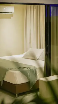 a bedroom with a bed with white sheets and a window at Talam House Coveñas by Bernalo Hotels in Coveñas