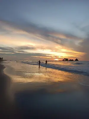 two people standing on the beach at sunset at Eywa Lodge in Pueblo Coco