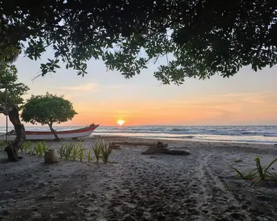 a boat on the beach with the sunset in the background at Eywa Lodge in Pueblo Coco