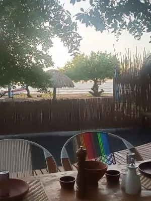 a table with a colorful chair at a table with a view of the beach at Eywa Lodge in Pueblo Coco
