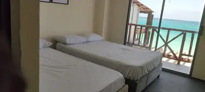 two beds in a room with a view of the ocean at Hotel Miramar Baru in Playa Blanca