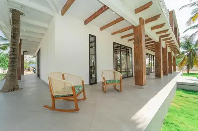 a porch of a house with chairs and palm trees at Villa de lujo frente al mar en Tierra Bomba in Cartagena de Indias