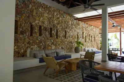 a lobby with a stone wall and tables and chairs at BaiaKristal - Kabo en Cartagena in Cartagena de Indias