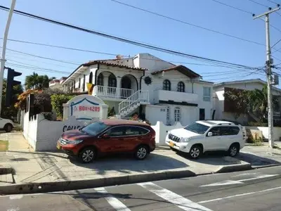 two cars parked in a parking lot in front of a house at B&B GRANDRoyal Inn in Barranquilla
