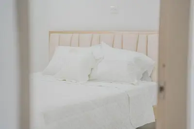 a white bed with white sheets and pillows at lujoso apartamento familiar frente al mar in Cartagena de Indias