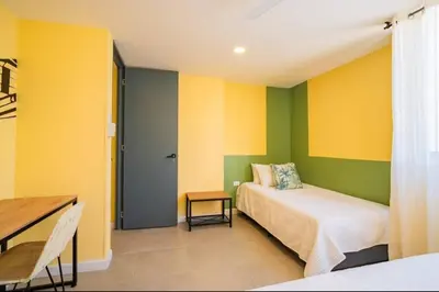a bedroom with yellow and green walls and a bed at Laguito Houstel Large in Cartagena de Indias