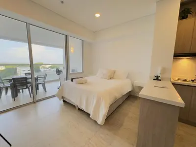 a bedroom with a bed and a kitchen with a balcony at Apartamento suite Cartagena - Cartagena Beach Resort in Cartagena de Indias